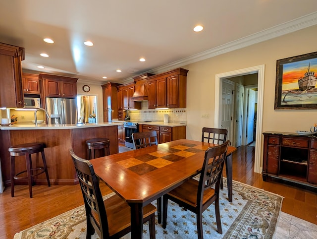 dining room with ornamental molding, recessed lighting, and light wood-style floors