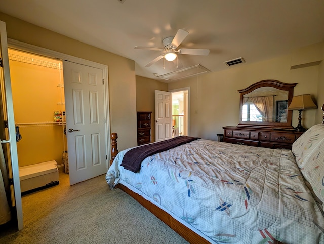 bedroom featuring carpet floors, visible vents, a spacious closet, attic access, and ceiling fan