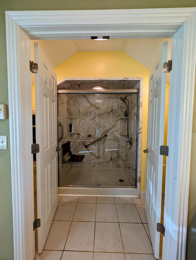 full bath featuring tile patterned flooring, vaulted ceiling, and a marble finish shower