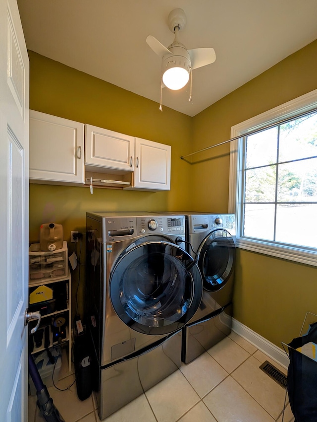 clothes washing area with light tile patterned floors, cabinet space, visible vents, washing machine and dryer, and baseboards