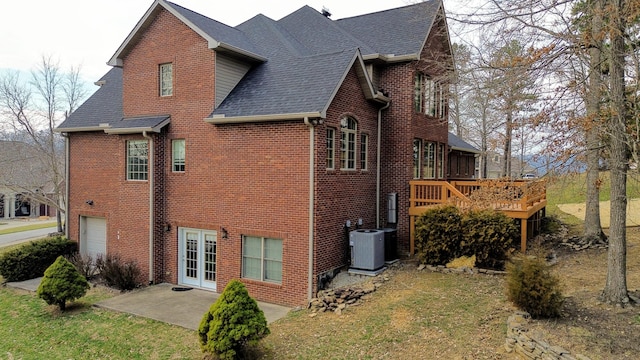 view of home's exterior featuring a deck, a patio, central AC unit, brick siding, and a yard