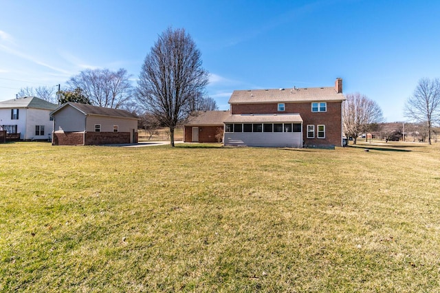 rear view of property with a sunroom, a yard, and a chimney