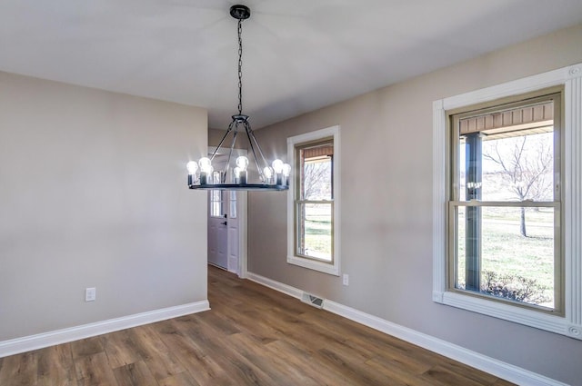 unfurnished dining area featuring plenty of natural light, baseboards, visible vents, and a chandelier