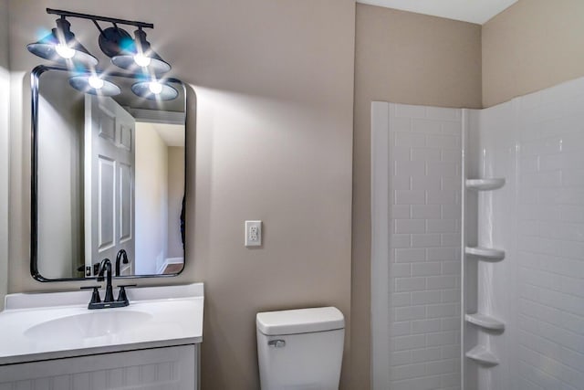 bathroom featuring toilet, a shower, and vanity