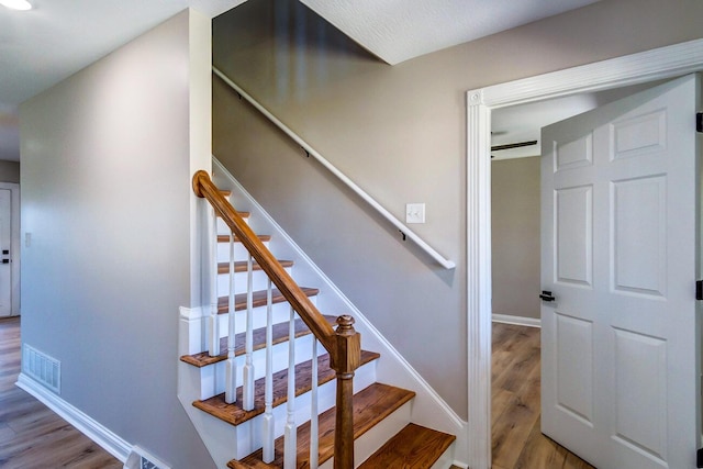 staircase featuring visible vents, baseboards, and wood finished floors