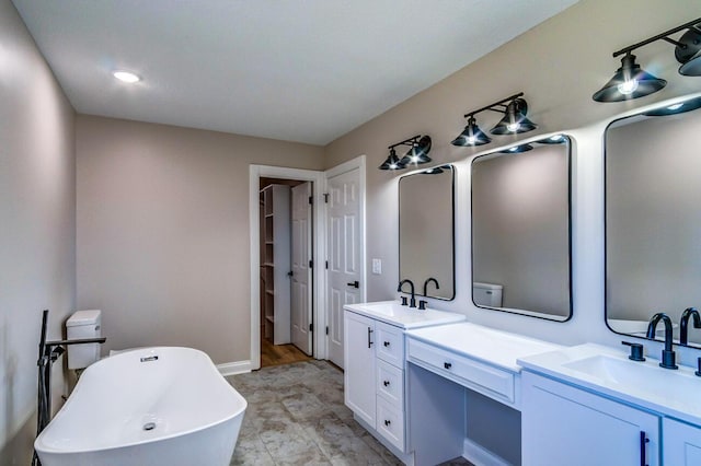 full bath with double vanity, a freestanding tub, baseboards, and a sink