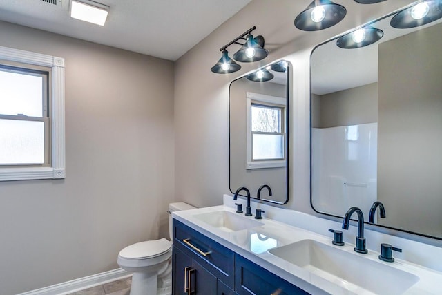 bathroom featuring baseboards, a sink, toilet, and double vanity