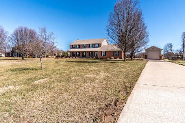 view of front of home featuring a garage, concrete driveway, an outdoor structure, a front lawn, and brick siding