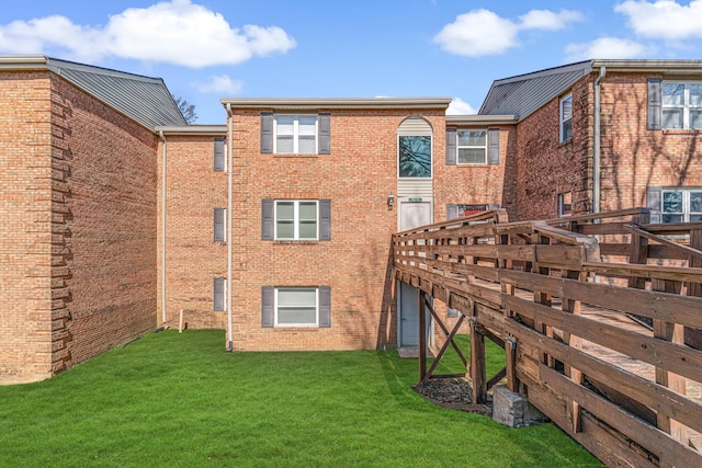 rear view of property with a lawn and brick siding