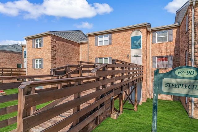 back of property featuring a lawn and brick siding