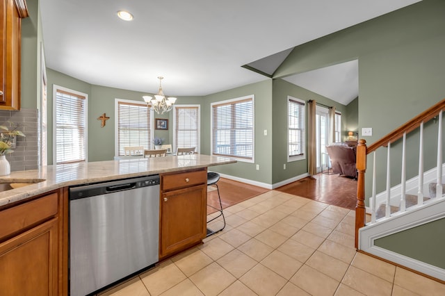 kitchen with tasteful backsplash, brown cabinets, dishwasher, and light tile patterned flooring