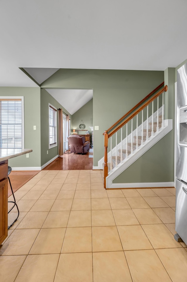 tiled foyer with lofted ceiling, stairway, and baseboards