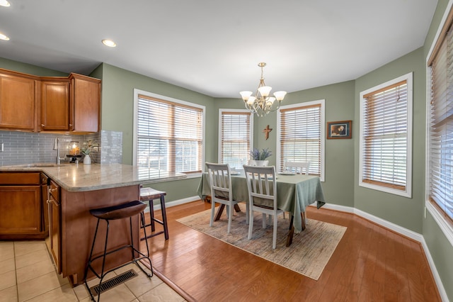 dining space featuring baseboards, visible vents, light wood-type flooring, a chandelier, and recessed lighting