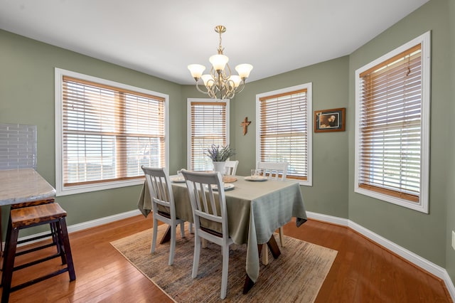 dining area with an inviting chandelier, baseboards, and hardwood / wood-style flooring