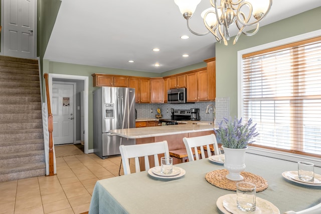 interior space with appliances with stainless steel finishes, a peninsula, a sink, light countertops, and backsplash