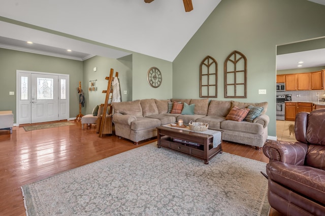 living area with high vaulted ceiling, ornamental molding, wood finished floors, and baseboards