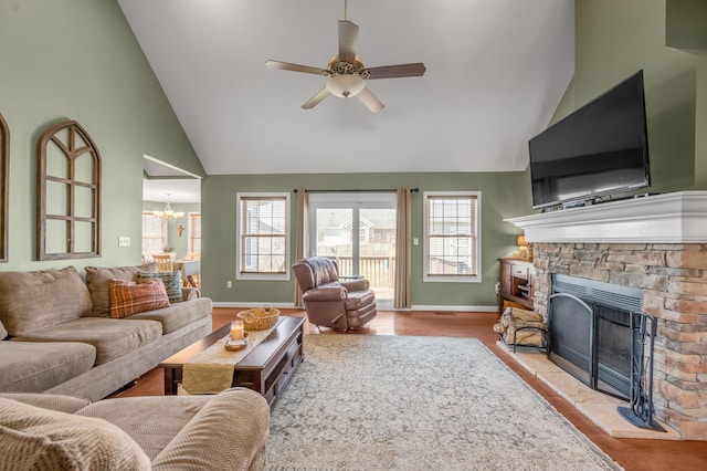 living room with high vaulted ceiling, ceiling fan with notable chandelier, a fireplace, wood finished floors, and baseboards