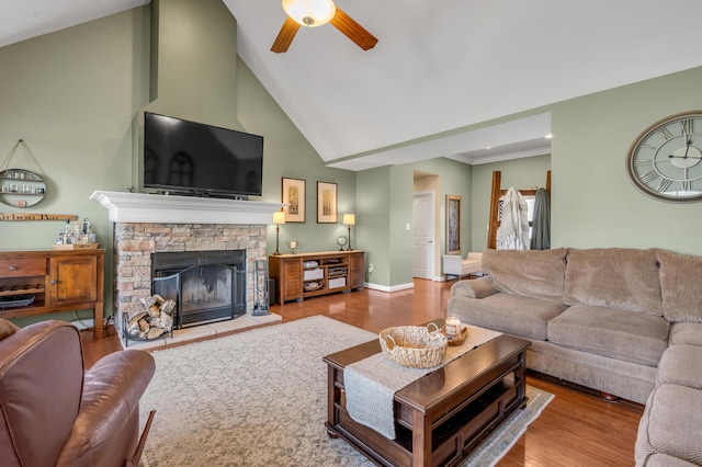 living area with ceiling fan, a fireplace, high vaulted ceiling, and wood finished floors