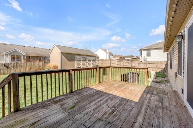 wooden terrace featuring a fenced backyard, a residential view, a lawn, and an outbuilding