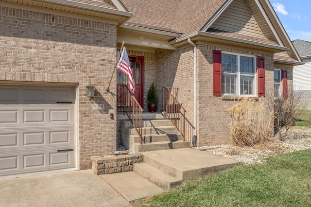 view of exterior entry featuring a garage, brick siding, and roof with shingles