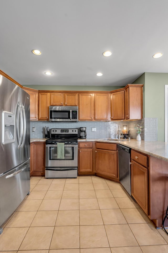 kitchen featuring brown cabinets, light stone countertops, stainless steel appliances, and light tile patterned flooring