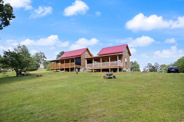 back of property featuring a wooden deck, a lawn, and metal roof