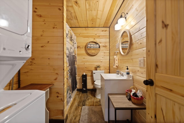 full bathroom featuring stacked washer and dryer, wood ceiling, wooden walls, and toilet