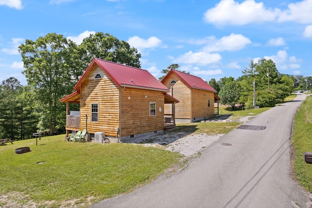 view of home's exterior featuring crawl space, metal roof, aphalt driveway, and a yard