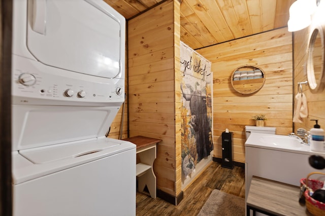 washroom featuring laundry area, a sink, stacked washer / drying machine, wood walls, and wooden ceiling