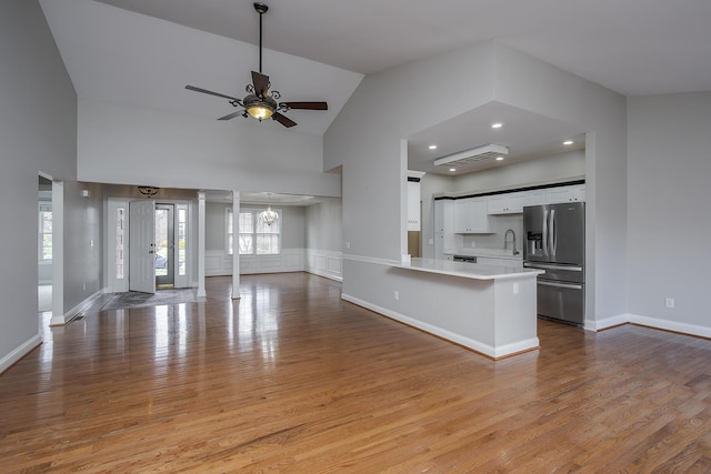 kitchen with light countertops, open floor plan, white cabinets, wood finished floors, and stainless steel fridge with ice dispenser