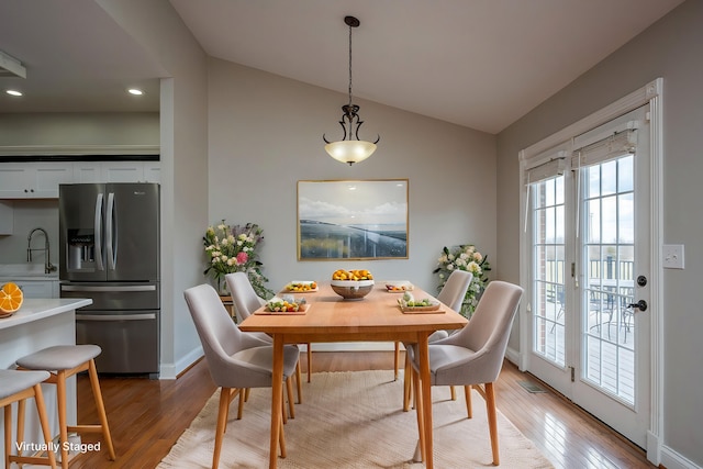 dining space featuring lofted ceiling, light wood-style floors, visible vents, and baseboards