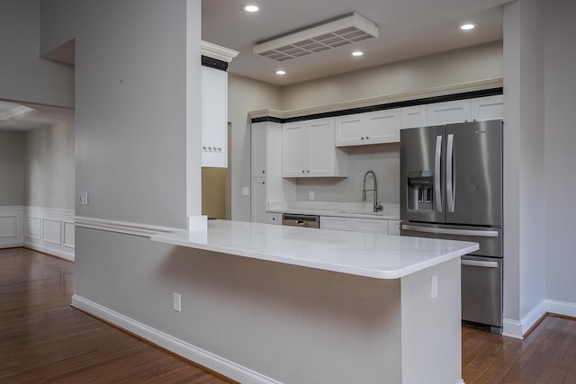 kitchen with white cabinets, dark wood-style flooring, a peninsula, stainless steel appliances, and recessed lighting