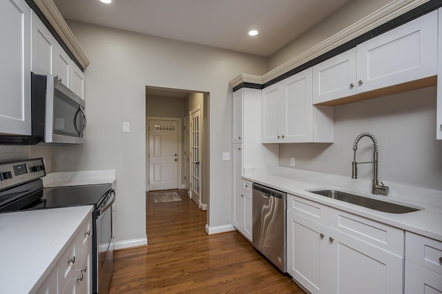 kitchen with appliances with stainless steel finishes, dark wood finished floors, light countertops, and a sink