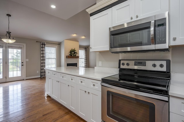 kitchen with pendant lighting, stainless steel appliances, light countertops, white cabinets, and light wood-type flooring