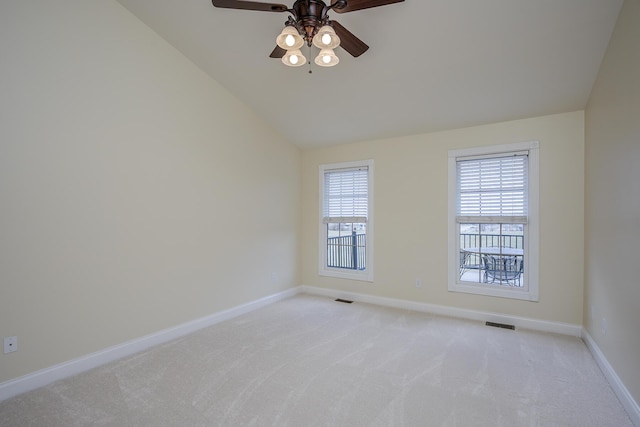 spare room featuring light carpet, lofted ceiling, visible vents, and baseboards