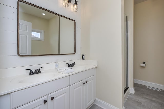 full bathroom with double vanity, baseboards, visible vents, and a sink