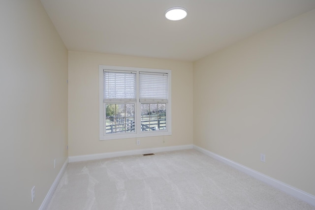 unfurnished room with light carpet, visible vents, and baseboards