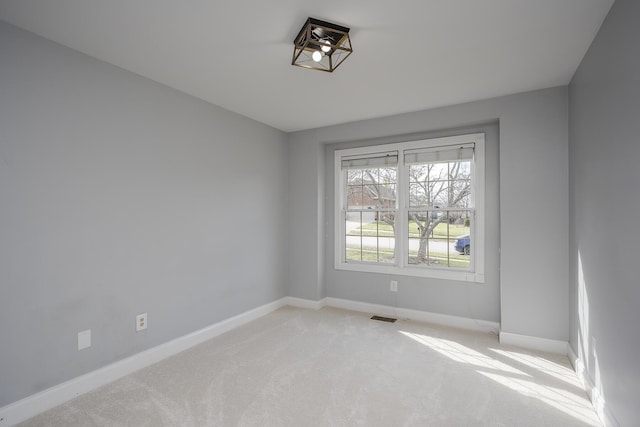 unfurnished room featuring baseboards, visible vents, and light colored carpet