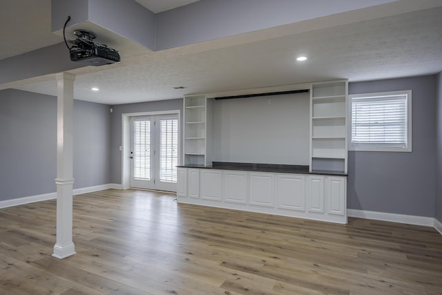 unfurnished living room featuring decorative columns, baseboards, a textured ceiling, light wood-style floors, and recessed lighting