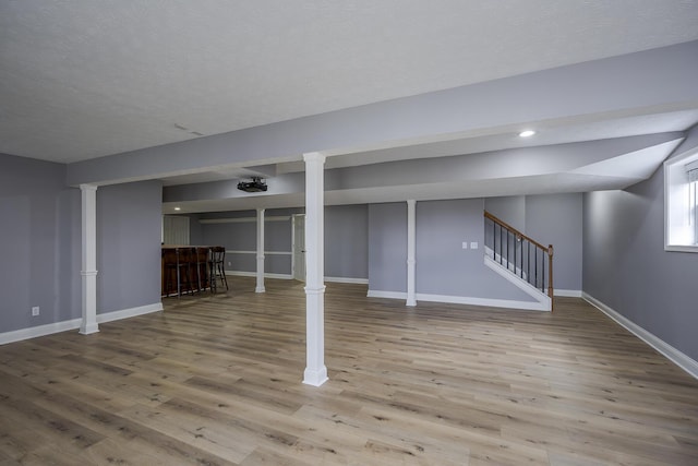 basement featuring baseboards, wood finished floors, stairs, a bar, and recessed lighting