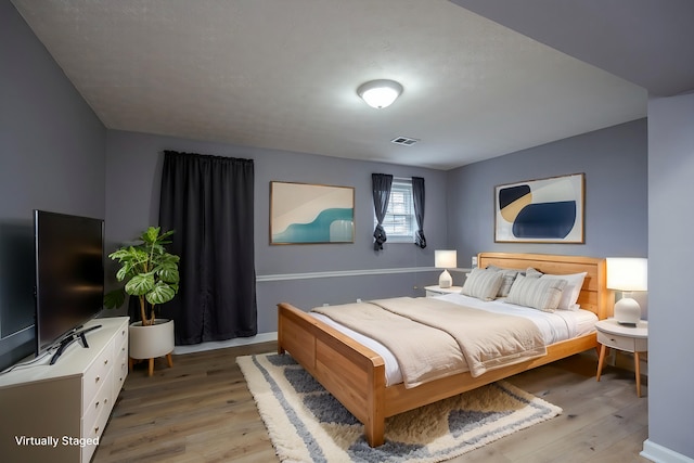 bedroom with light wood-style floors and visible vents