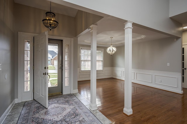 foyer featuring a decorative wall, wainscoting, decorative columns, and an inviting chandelier