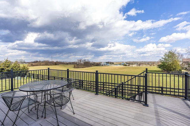 wooden deck featuring a yard, outdoor dining space, and a rural view