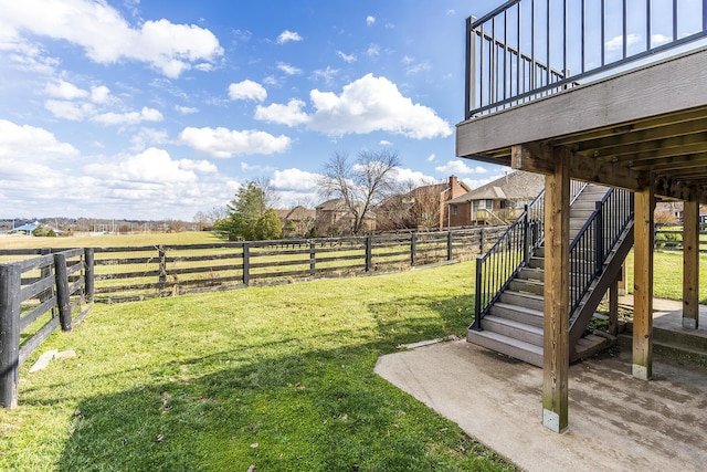 view of yard featuring a fenced backyard, stairway, and a rural view