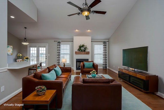 living room with lofted ceiling, a fireplace, wood finished floors, and a healthy amount of sunlight