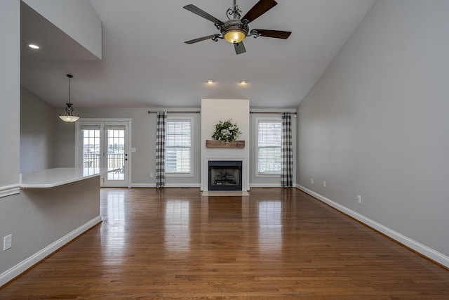 unfurnished living room featuring a fireplace with flush hearth, vaulted ceiling, and wood finished floors