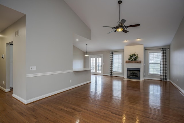 unfurnished living room featuring baseboards, visible vents, a ceiling fan, a fireplace with flush hearth, and wood finished floors