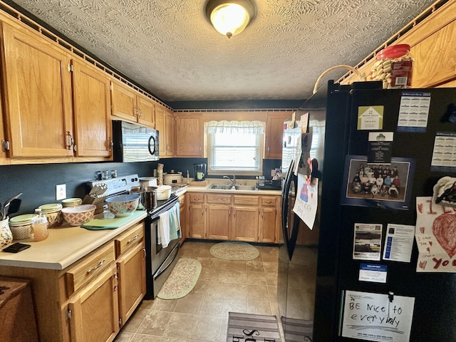 kitchen featuring a textured ceiling, black appliances, a sink, and light countertops