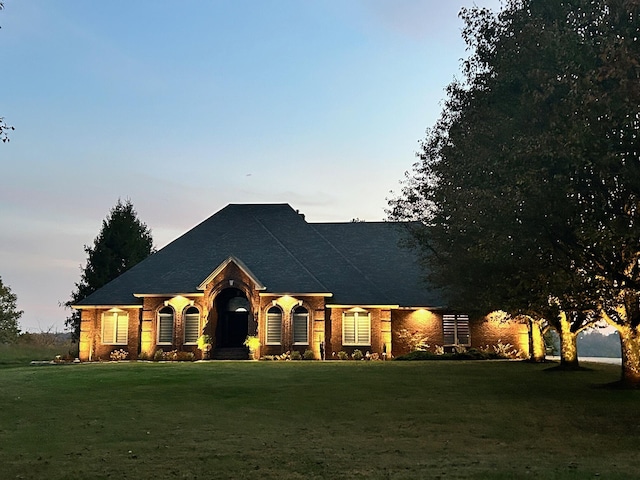 view of front of property with a lawn and brick siding