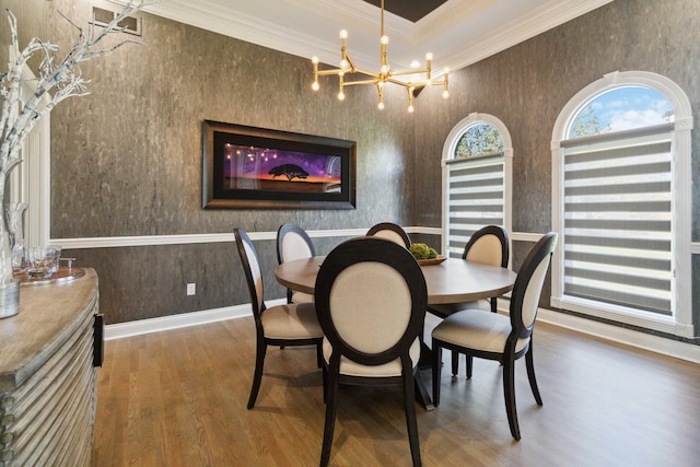 dining space with baseboards, ornamental molding, a chandelier, and wood finished floors